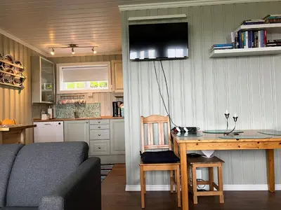 a living room with a table and a tv on the wall at Skiidyll Med Utsikt Og Peis in Beitostøl
