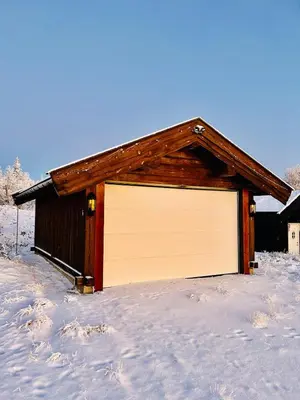 a building with a white garage door in the snow at Cosy family cabin in Trysil in Trysil