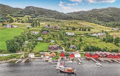 a boat in the water next to a village at 10 Bedroom Amazing Home In Ølen in Ølen