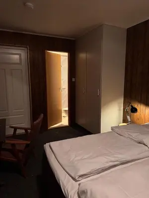 a bedroom with a bed and a chair and a door at Ustedalen Lodge in Geilo