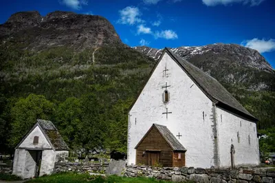 an old church in front of a mountain at Huse Gjestegard in Kinsarvik