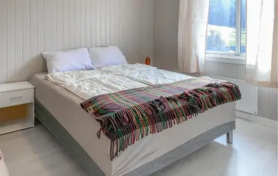 a bed with a blanket on it in a bedroom at Gorgeous Home In Åheim in Åheim