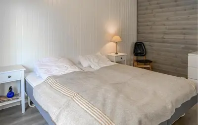 a bedroom with a large bed and a table with a lamp at Gorgeous Home In Åheim in Åheim