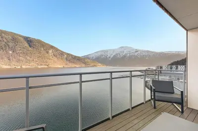 a chair on a balcony overlooking a body of water at Penthouse with fjord view and parking in Sogndal