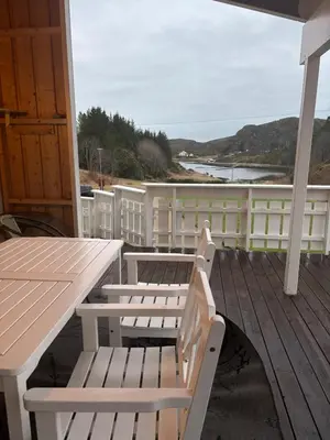 a porch with two white benches and a table at Fjærestua in Hitra