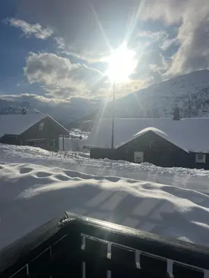 a snow covered roof of a house with the sun shining at Apartment Røldal in Håra