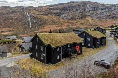 a black house with a grass roof on a road at Apartment Røldal in Håra