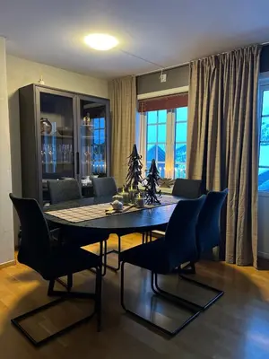 a dining room with a table and chairs and a couch at Apartment Røldal in Håra