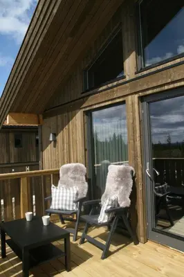 a patio with two chairs and a table on a deck at Sjusjøen Hytteutleie AS in Sjusjøen