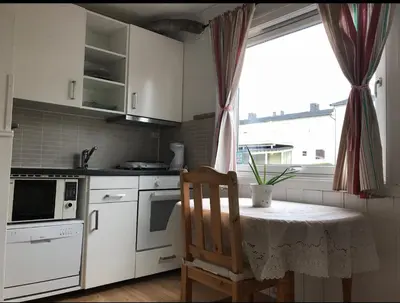 a kitchen with a table with a chair and a window at Cozy small bedroom flat in Trondheim