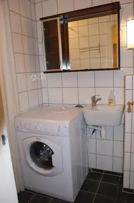 a bathroom with a washing machine and a sink at Cozy small bedroom flat in Trondheim