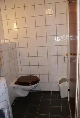 a bathroom with a toilet with a wooden seat at Cozy small bedroom flat in Trondheim