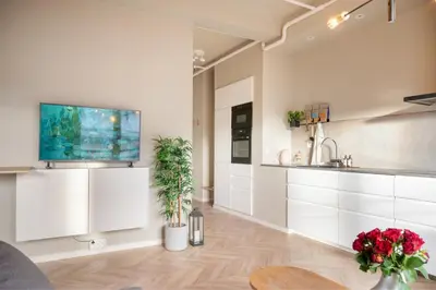 a kitchen with white cabinets and a tv on the wall at 3F - In the heart of Trondheim in Trondheim