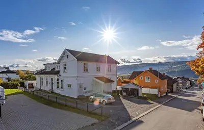 a white house with a car parked in a street at Bright and nice downtown apartment in Lillehammer
