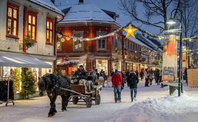 a horse drawn carriage on a snowy street with people at Bright and nice downtown apartment in Lillehammer