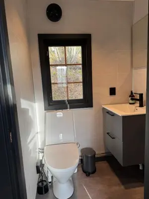 a bathroom with a toilet and a sink and a window at Smart and beautiful micro house - Great base for mountain adventures in Hedalen