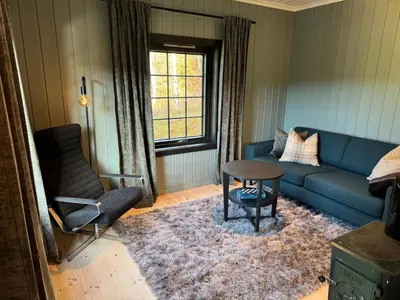 a living room with a blue couch and a chair at Smart and beautiful micro house - Great base for mountain adventures in Hedalen