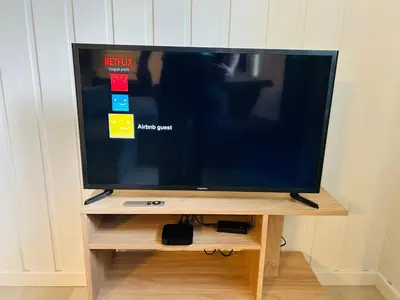 a flat screen tv sitting on a wooden stand at Central apartment - Free parking and Wi-Fi in Lillehammer