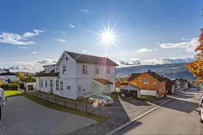 a white house with a car parked in a street at Central apartment - Free parking and Wi-Fi in Lillehammer