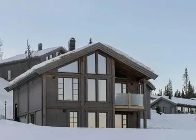 a large wooden house with windows in the snow at Premium Cabin By Kvitfjell Ski Slopes in Ringebu