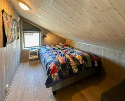 a bedroom with a bed in a wooden room at Architect Designed Cabin With Panoramic Views in Ål