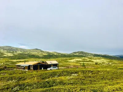 a house in the middle of a field with a car at Architect Drawn Holiday Home Near Rondane Park in Høvringen