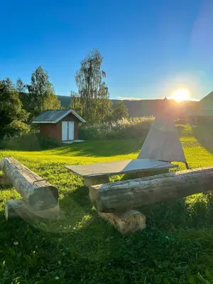 a wooden bench in a field with the sun setting at Historic Old Rectory In The Heart Of Norway in Vestre Gausdal