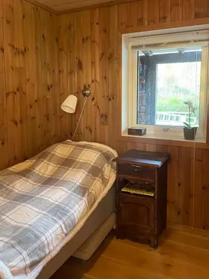 a bedroom with a bed with a lamp and a window at Sunny Cabin With Fjord Views In Redal in Naustdal i Sunnfjord