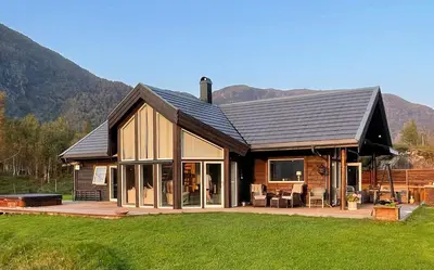 a large wooden house with a deck and a house at Sunny Cabin With Fjord Views In Redal in Naustdal i Sunnfjord