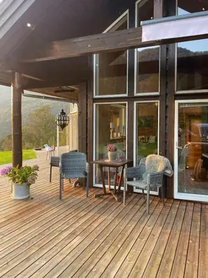 a wooden deck with chairs and a table on a house at Sunny Cabin With Fjord Views In Redal in Naustdal i Sunnfjord