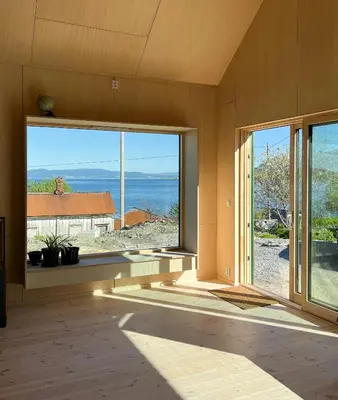 an empty room with large windows and a view of the ocean at Architect-Designed Cabin With Beach Nearby in Lensvik