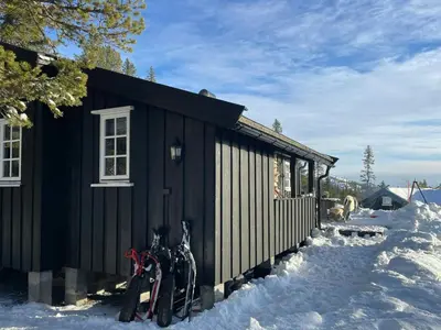 a black cabin in the snow with skis next to it at Cabin By The Cross-Country Trails In Norefjell in Eggedal