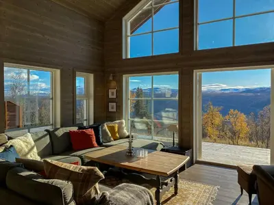 a living room with a table and large windows at Traditional Cabin With Views Of Hardangervidda in Uvdal
