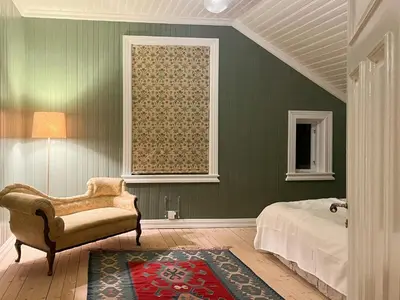a bedroom with green walls and a chair and a window at Historic Property In Idyllic Snertingdal in Segard