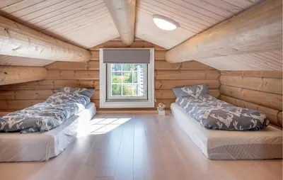 two beds in a room with wooden walls and a window at Amazing Home In Lesjaskog With Wifi in Bjorli