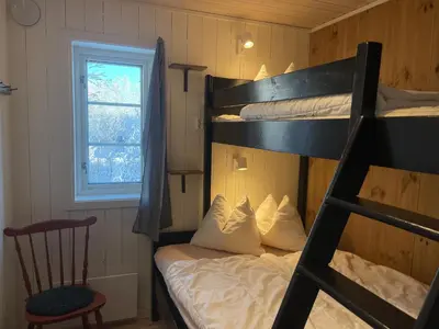 a bedroom with a bunk bed with a chair and a window at New 4Bedroom Cabin With Sauna, Terrace & Fireplace in Beitostøl