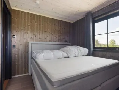a bedroom with a white bed in a wooden wall at Trysil turistesenter hytte in Trysil