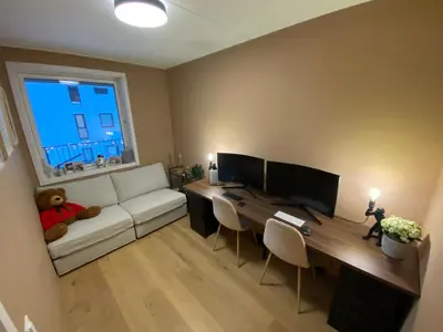 a living room with a couch and a desk with two monitors at Modern, big and central apartment in Trondheim in Trondheim