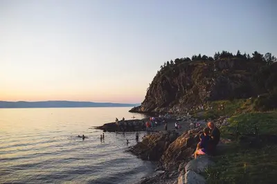 a group of people sitting on a beach near the water at Modern, big and central apartment in Trondheim in Trondheim