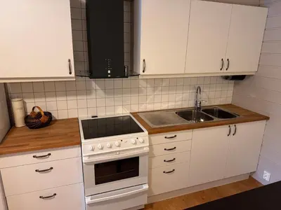 a kitchen with white cabinets and a sink at 2 roms kjellerleilighet med separat soverom in Luster