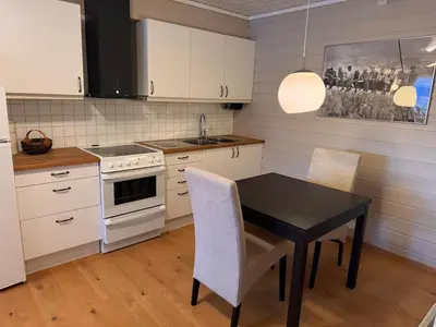 a kitchen with a black table and white cabinets at 2 roms kjellerleilighet med separat soverom in Luster