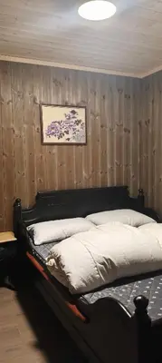 a bedroom with a bed with a wooden wall at Trysil turistesenter liten leilighet in Trysil