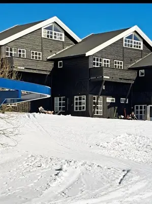 a black barn in the snow in front at Ski inn Ski Out Best holiday Apartments i Oppdal in Oppdal