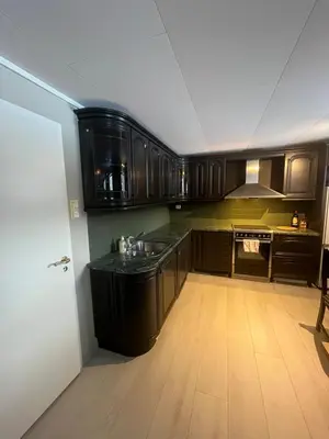 a kitchen with wooden cabinets and a wooden floor at Sokkelleilighet i enebolig in Sula