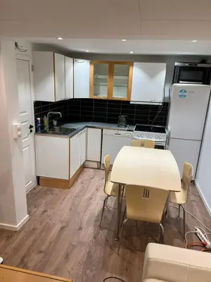 a kitchen with white cabinets and a table and chairs at Gjestehus i Trondheim, under VM 2025 in Trondheim