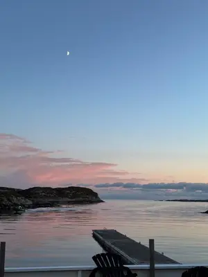 a dock with a boat in the water at sunset at Cozy Oceanfront Escape in Nautnes