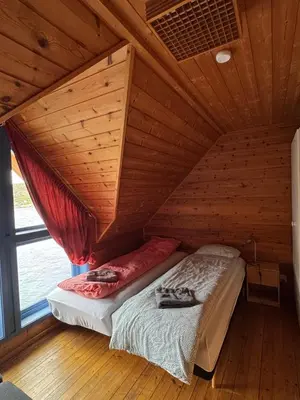 a bed in a room with a wooden ceiling at Cozy Oceanfront Escape in Nautnes