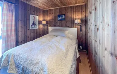 a bedroom with a bed in a wooden wall at Cozy Home In Sjusjøen With Sauna in Sjusjøen