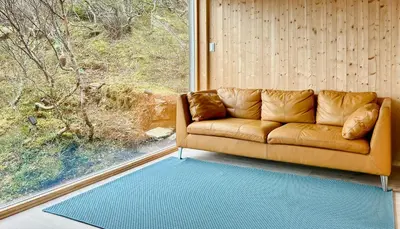 a brown couch in a room with a window at Architect Drawn Cabin With Sea View At Stokkøy in Hosen
