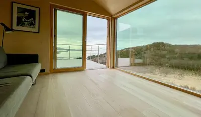 a living room with a couch and a large window at Architect Drawn Cabin With Sea View At Stokkøy in Hosen